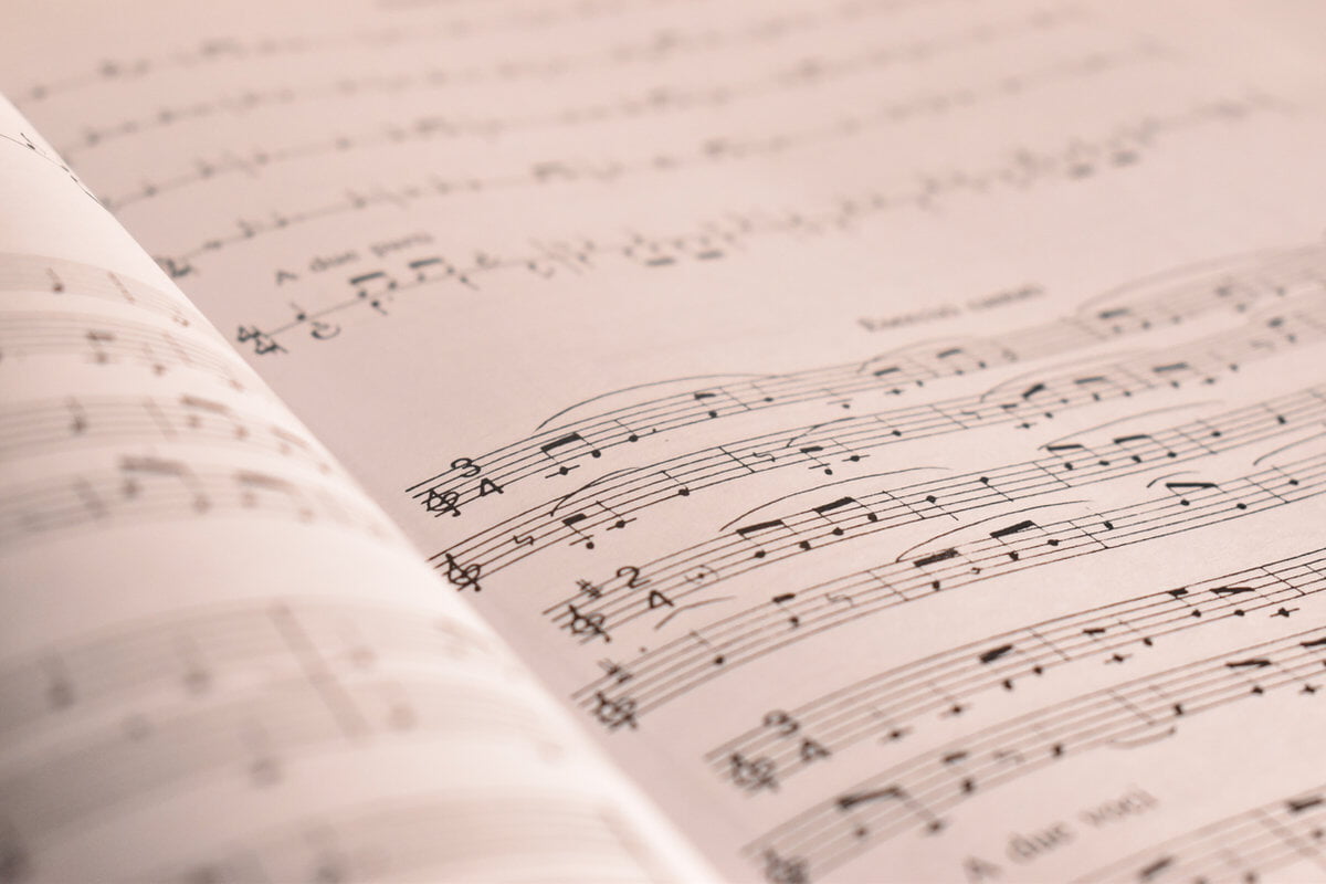 Close-up of an open music sheet with black notes and lines on a cream background, creating an artistic and serene mood.